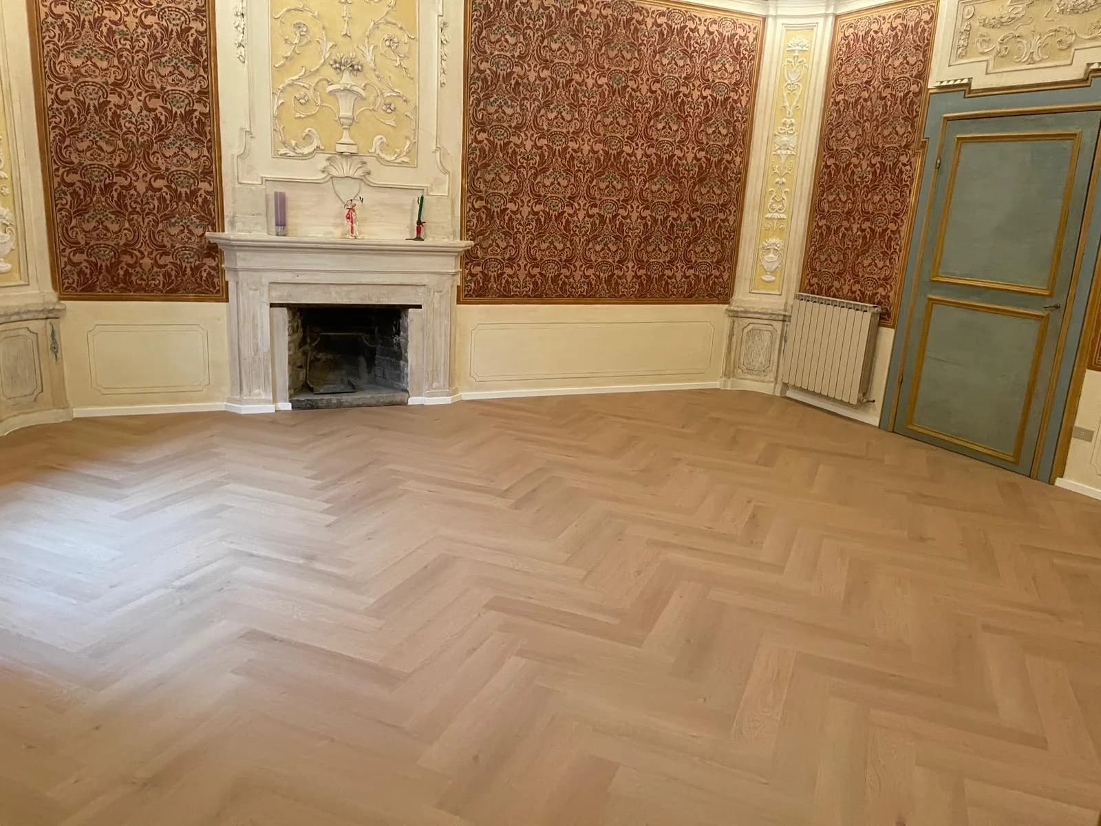Sala affrescata di un palazzo storico con pavimento a spina di pesce appena posato